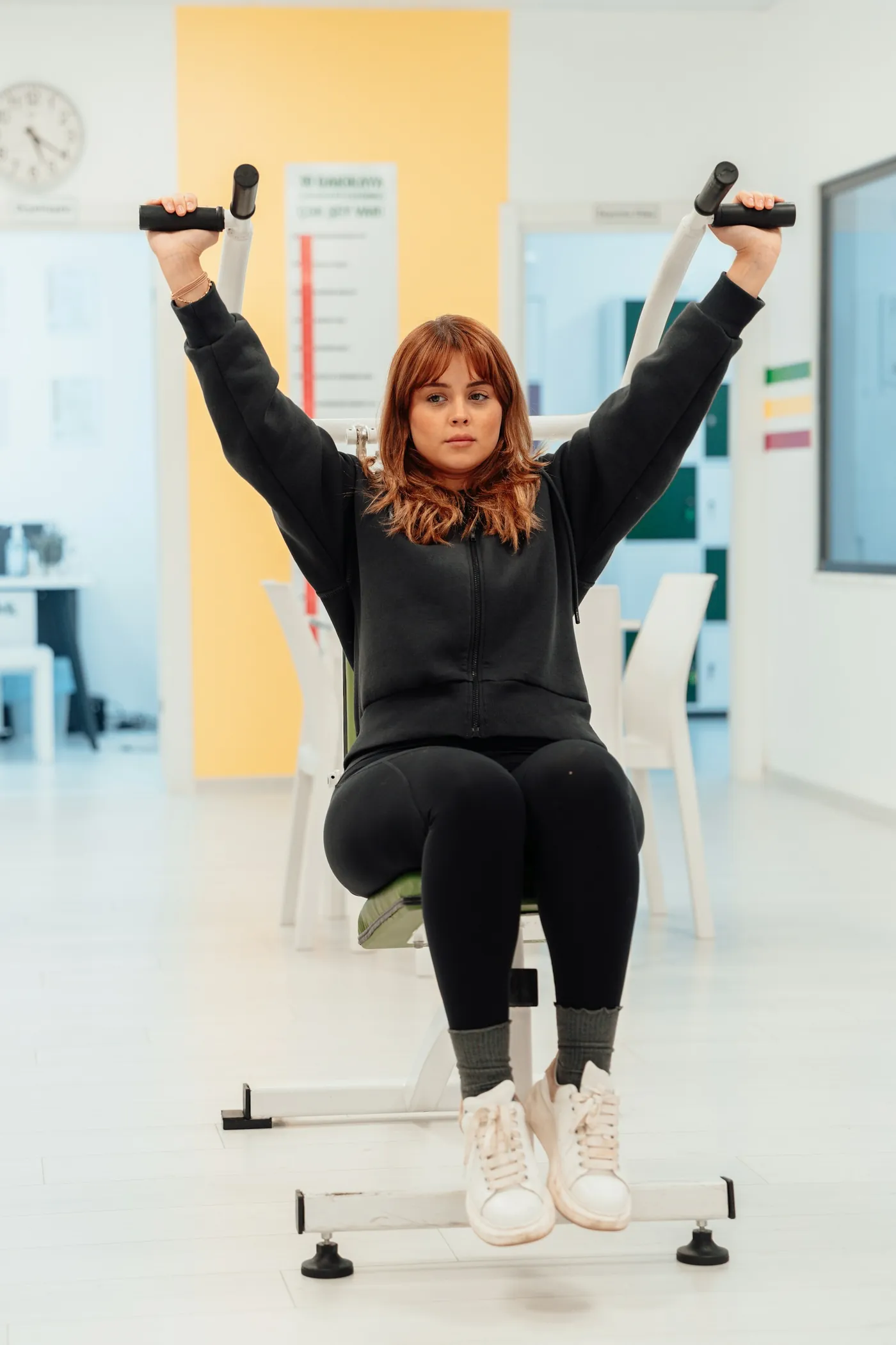 Mulher madura treinando com halteres em uma sala clara.