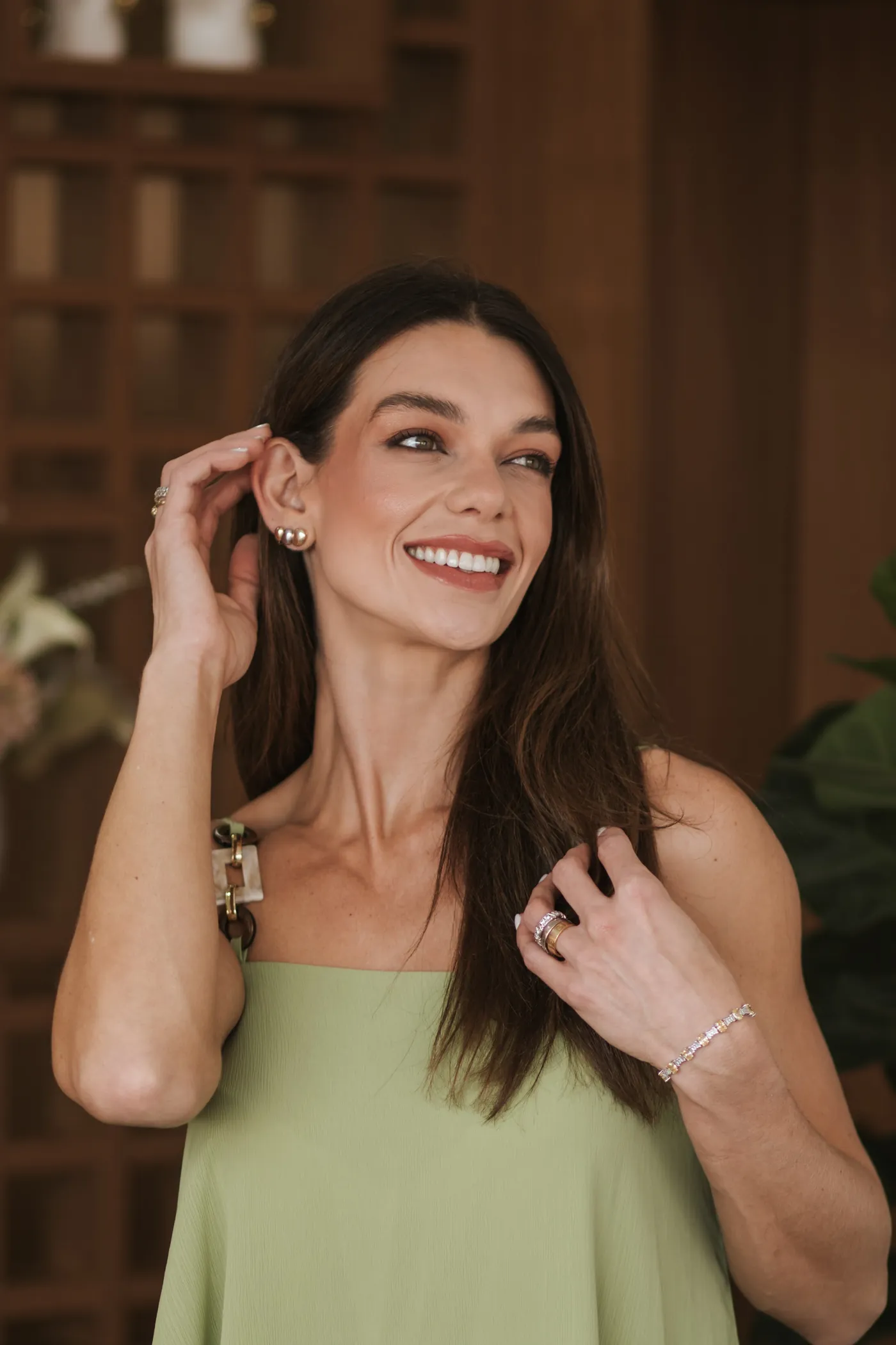 Dra. Stella Cardoso de conjunto verde, sorrindo com a mão nos cabelos.